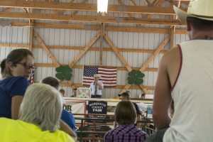 Auctioneer from the back of the packed barn during the livestock sale at the Marquette County Fair 2015